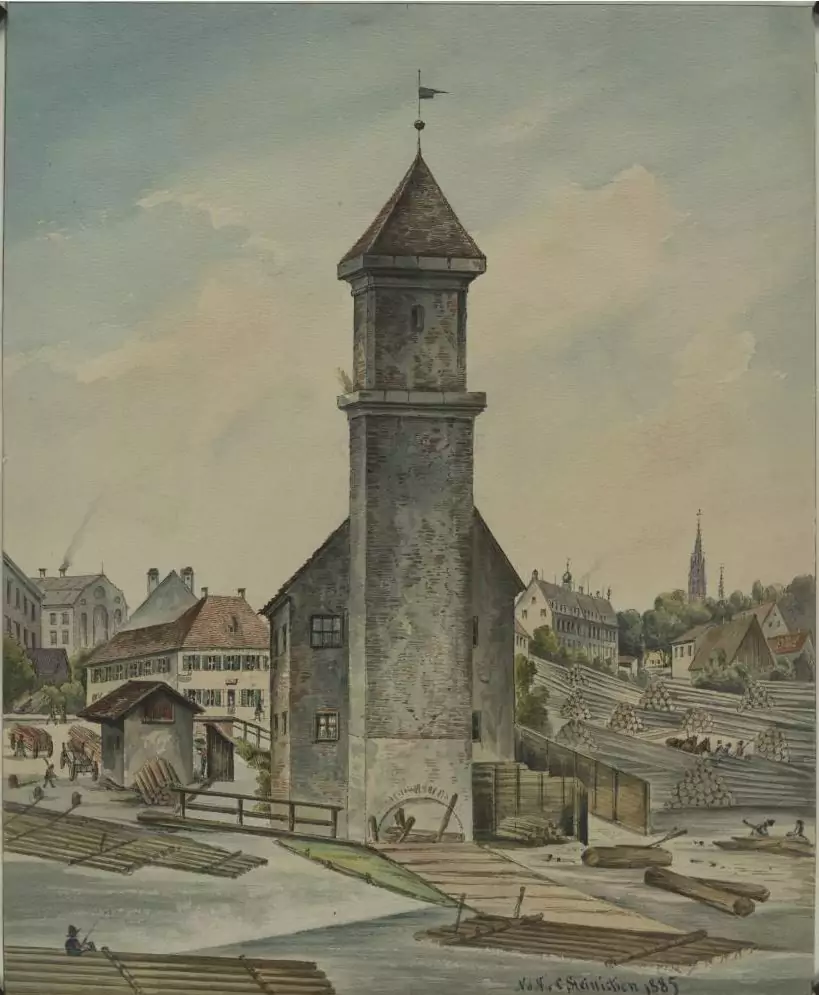 Ein hoher Steinturm steht an einem Fluss, in dem Baumstämme schwimmen, die die historische Praxis der Flößerei widerspiegeln; im Hintergrund sind mehrere Gebäude und Arbeiter zu sehen.