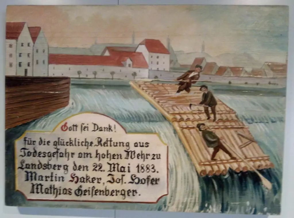 Eine gemalte Szene der Flößerei zeigt drei Männer auf einem Holzfloß in einem Fluss in der Nähe einer Stadt, mit einem deutschen Schild, das auf ihre Rettung aus der Gefahr am 22. Mai 1883 hinweist.