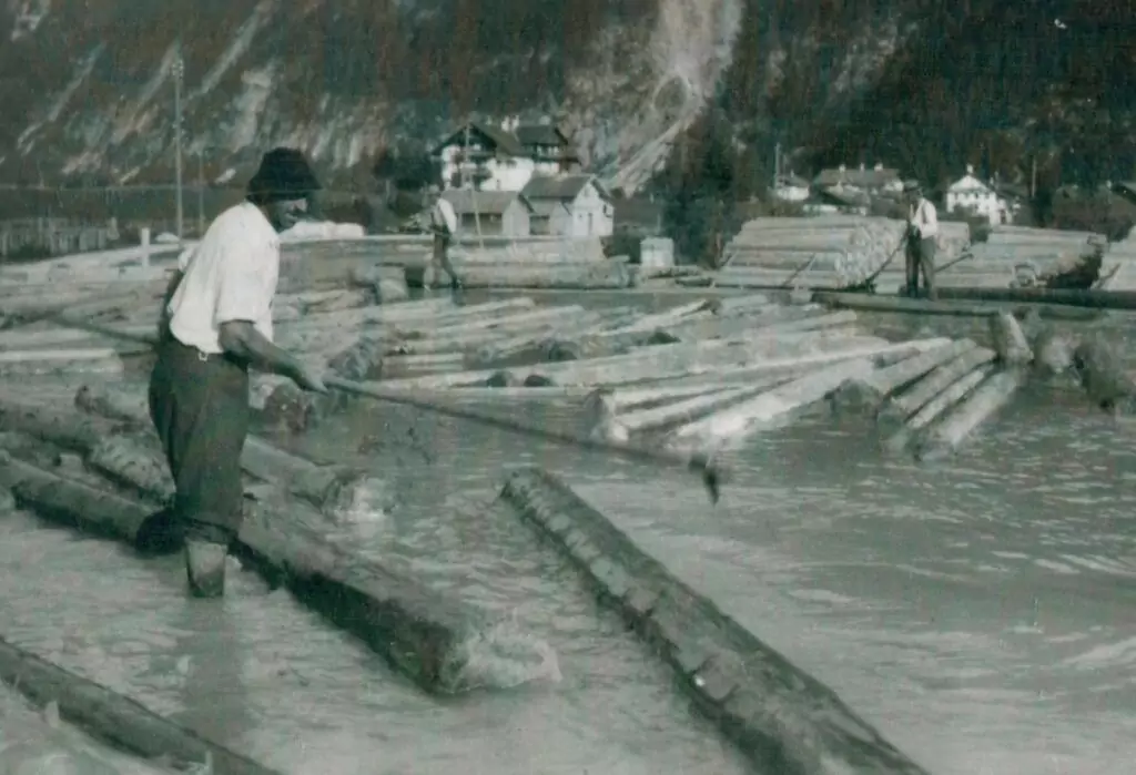 Ein Mann steht mit einem Stock im Wasser.