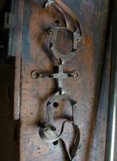 Ein Paar alter Holzerwerkzeuge mit Lederriemen ruht auf einer abgenutzten Holzfläche.