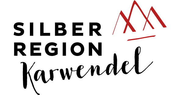 Logo mit dem Text „Silberregion Karwendel“ in fetter und kursiver Schrift, daneben eine schlichte rote Zeichnung von drei Berggipfeln.