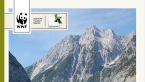 Ein Gebirgszug mit felsigen Gipfeln unter blauem Himmel, mit den Logos des WWF und des Naturparks Karwendel in der oberen linken Ecke, die die wilde Schönheit dieser alpinen Wildnis hervorheben.