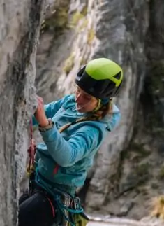 Eine Person, die einen Helm und eine Kletterausrüstung trägt, erklimmt eine felsige Outdoor-Felswand und zeigt damit ihre Leidenschaft für das Klettern im atemberaubenden Karwendelgebirge.