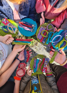 Eine Gruppe von Junior-Ranger-Teilnehmern mit bunten Kletterseilen, Karabinern und anderer Kletterausrüstung, von oben gesehen.