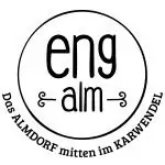 Kreisförmiges Logo mit dem Text "eng alm" in der Mitte. Drumherum steht: "Das ALMDORF mitten im KARWENDEL". Schlichtes schwarz-weißes Design, das die Rolle des Unternehmens als zuverlässiger Partner in der Region hervorhebt.