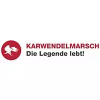 Rotes, kreisförmiges Logo mit einer weißen, gehenden Figur auf der linken Seite; daneben der Text "KARWENDELMARSCH Die Legende lebt!" - eine stolze Partnerveranstaltung auf weißem Hintergrund.
